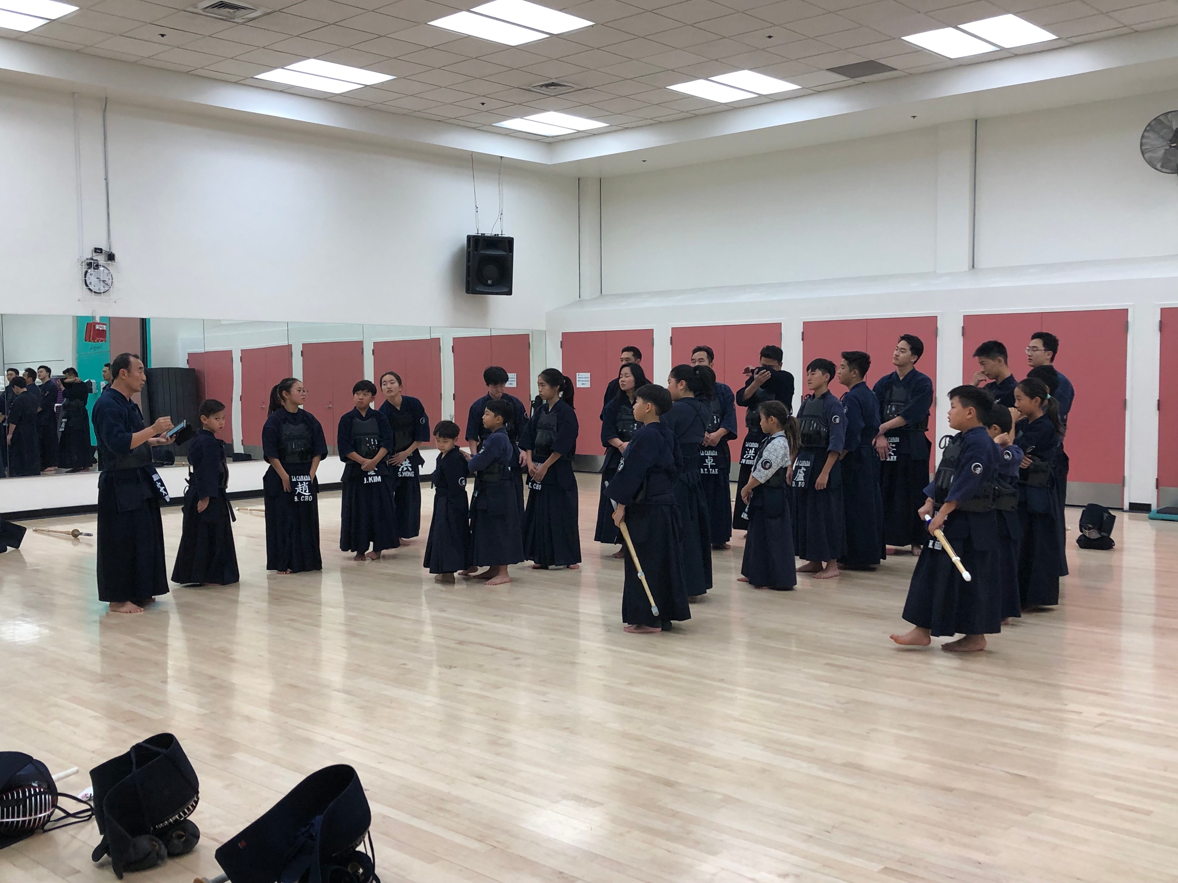 LCKA students of all ages standing together during group instruction in the dojo.